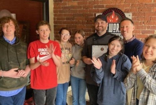A group of people smiling and standing in front of a restaurant.