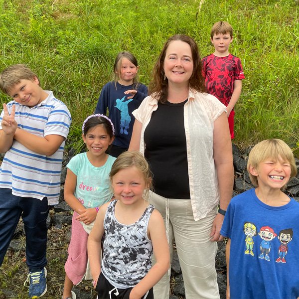 A woman standing in a group of six children.